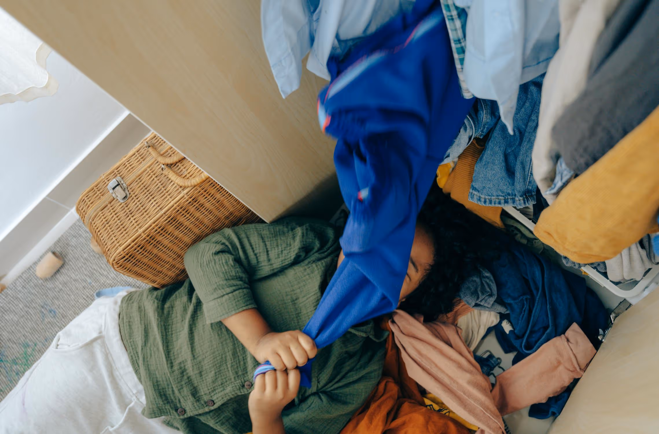 A woman laying on the ground surrounded by a large pile of items.