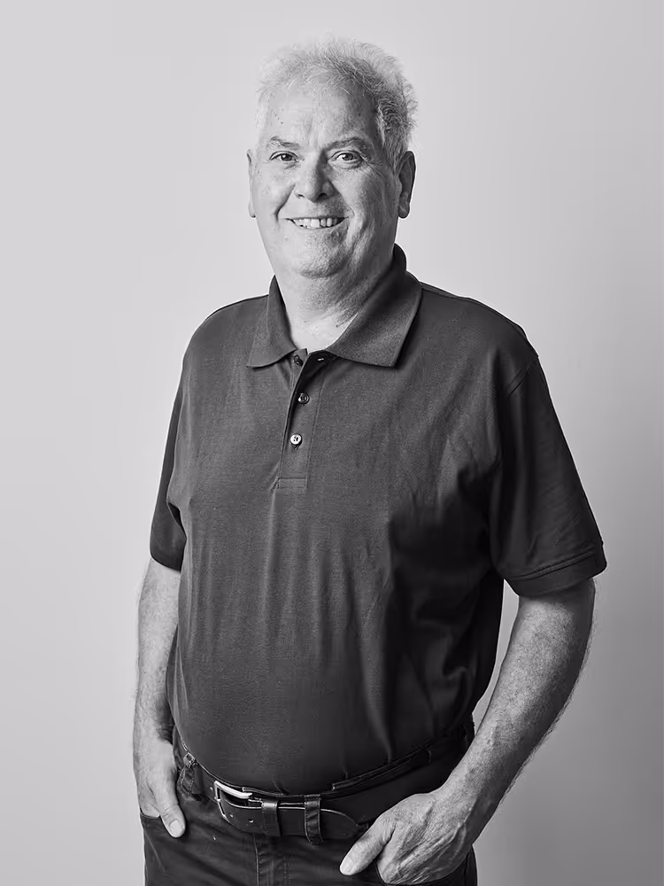 Porträt von Anton Riedl, Mitarbeiter bei Werndl Immobilienmanagement, lächelnd in einem Poloshirt, vor einem schlichten Hintergrund.