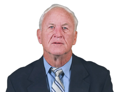 Elderly man with white hair wearing a dark suit, blue shirt, and striped tie, looking forward with a neutral expression.