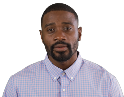 Man with short hair and beard wearing a blue and pink checkered button-up shirt looking at the camera.