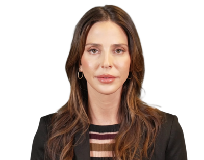 Portrait of a woman with long brown hair wearing a black blazer and striped top.