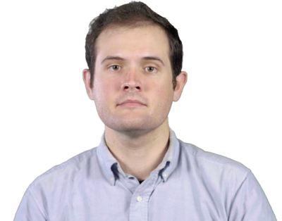 Man with light skin, dark hair, and wearing a light blue button-up shirt, facing forward with a neutral expression.