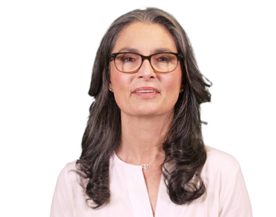 Middle-aged woman with long gray hair, glasses, and a white blouse smiling slightly.