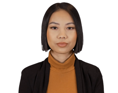 Portrait of a woman with straight black hair, wearing a mustard turtleneck and black blazer, looking forward with a neutral expression.