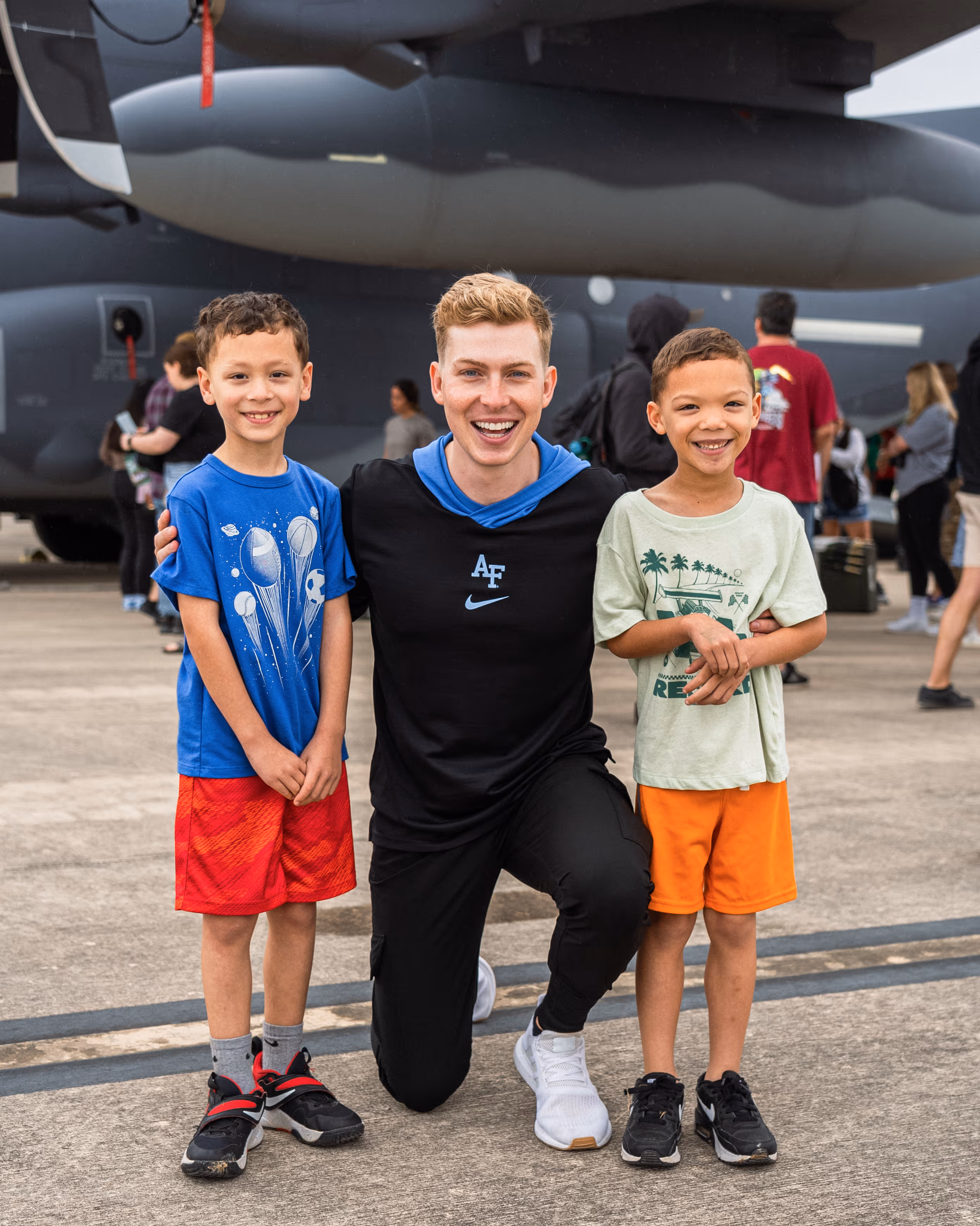 A picture of Sam Eckholm with 2 kids in front of a black plane