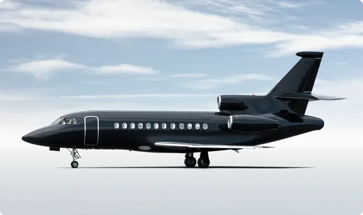 Black private jet aircraft on a flat surface with a cloudy sky background.