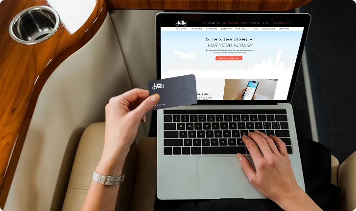 Black private jet aircraft on a flat surface with a cloudy sky background.