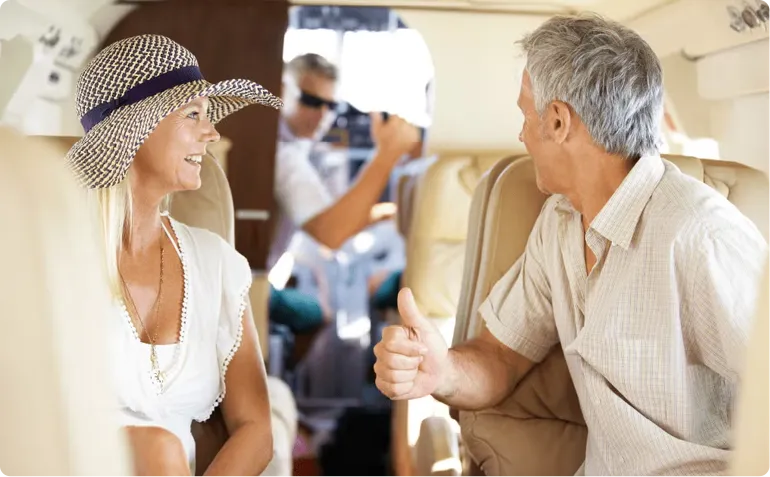 Person in a gray suit holding a credit card and using a smartphone next to an open laptop and a coffee cup on a table.