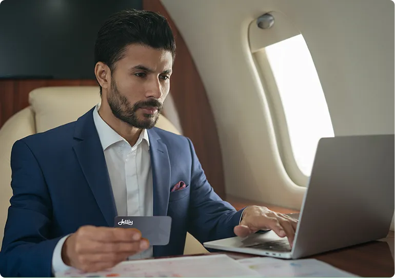 Woman with glasses sitting inside a private jet, holding a smartphone and looking out the window.