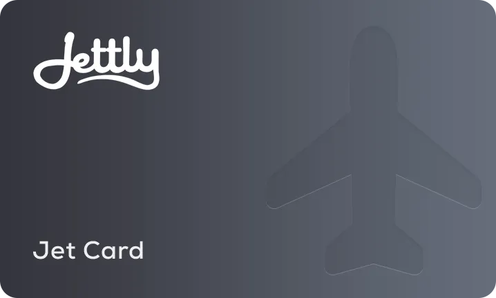 Woman with glasses sitting inside a private jet, holding a smartphone and looking out the window.