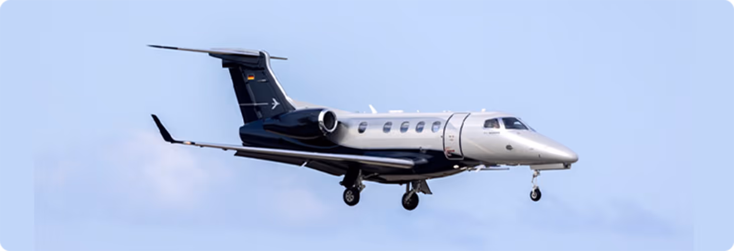 Small private jet with landing gear extended flying against a clear blue sky.
