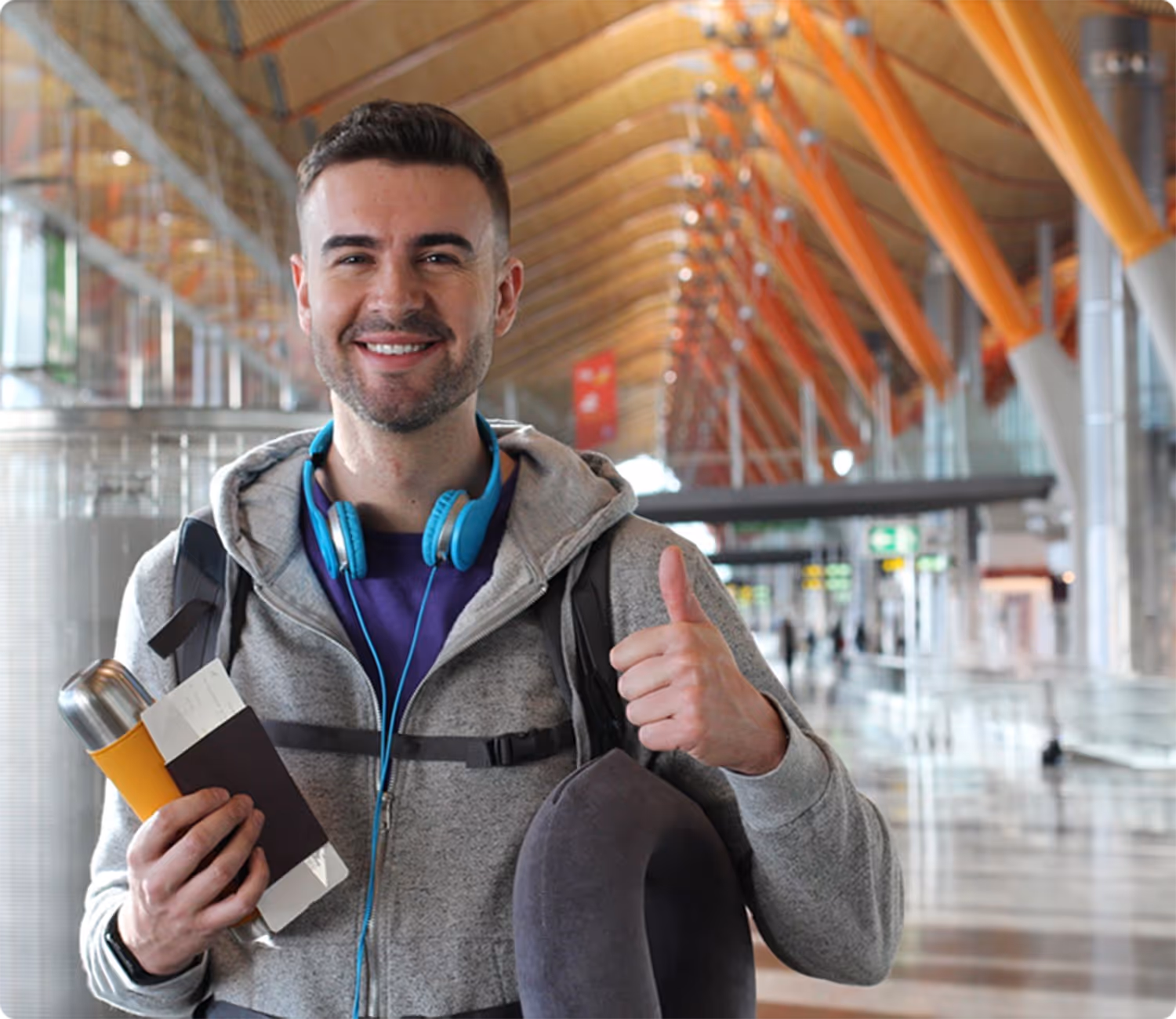 A man with headphones and a book giving a thumbs up.