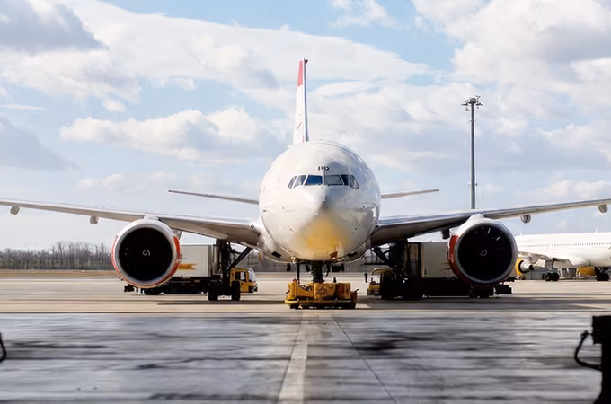 Front view of a large commercial airplane parked at an airport gate under a cloudy sky.