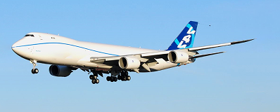 Large white cargo airplane with blue tail flying against clear blue sky.