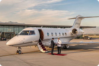Private jet parked on runway with open door, two men on red carpet near stairs at sunset.