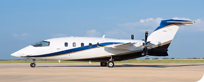White and blue private jet on runway with clear sky background.