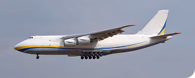 Large cargo airplane in flight with extended landing gear against a gray sky.