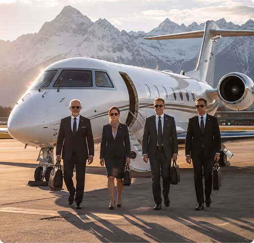 Four business professionals in suits walk on tarmac beside a private jet with snowy mountains behind them.