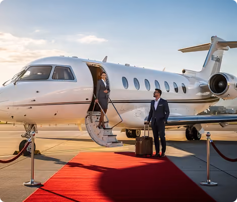 Businessman with suitcase and flight attendant boarding private jet on red carpet at sunset.