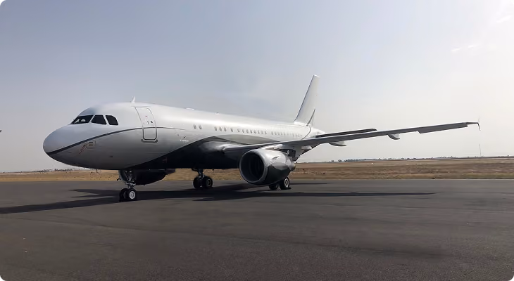 White commercial airplane parked on runway under clear sky during daytime.
