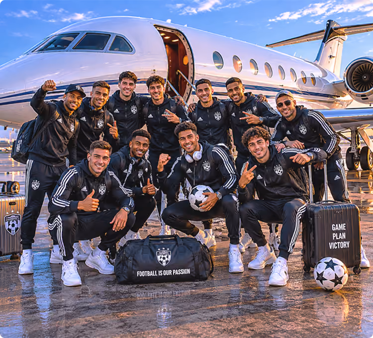 Group of soccer players in matching gear posing in front of a private jet with bags and soccer balls.
