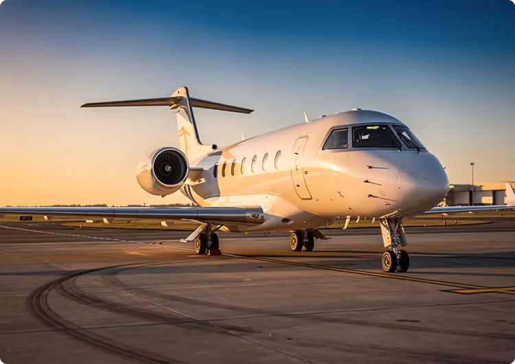 Private jet parked on airport tarmac during golden hour with clear sky in the background.