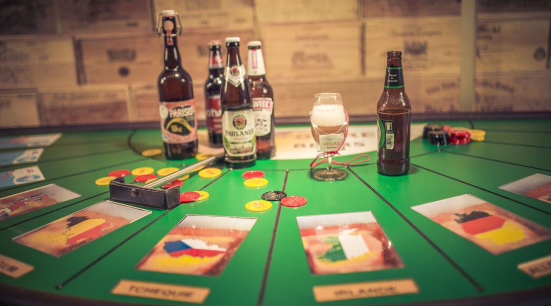 Green casino-style betting table with poker chips, a mini golf putter, several beer bottles, and a glass of beer with foam.