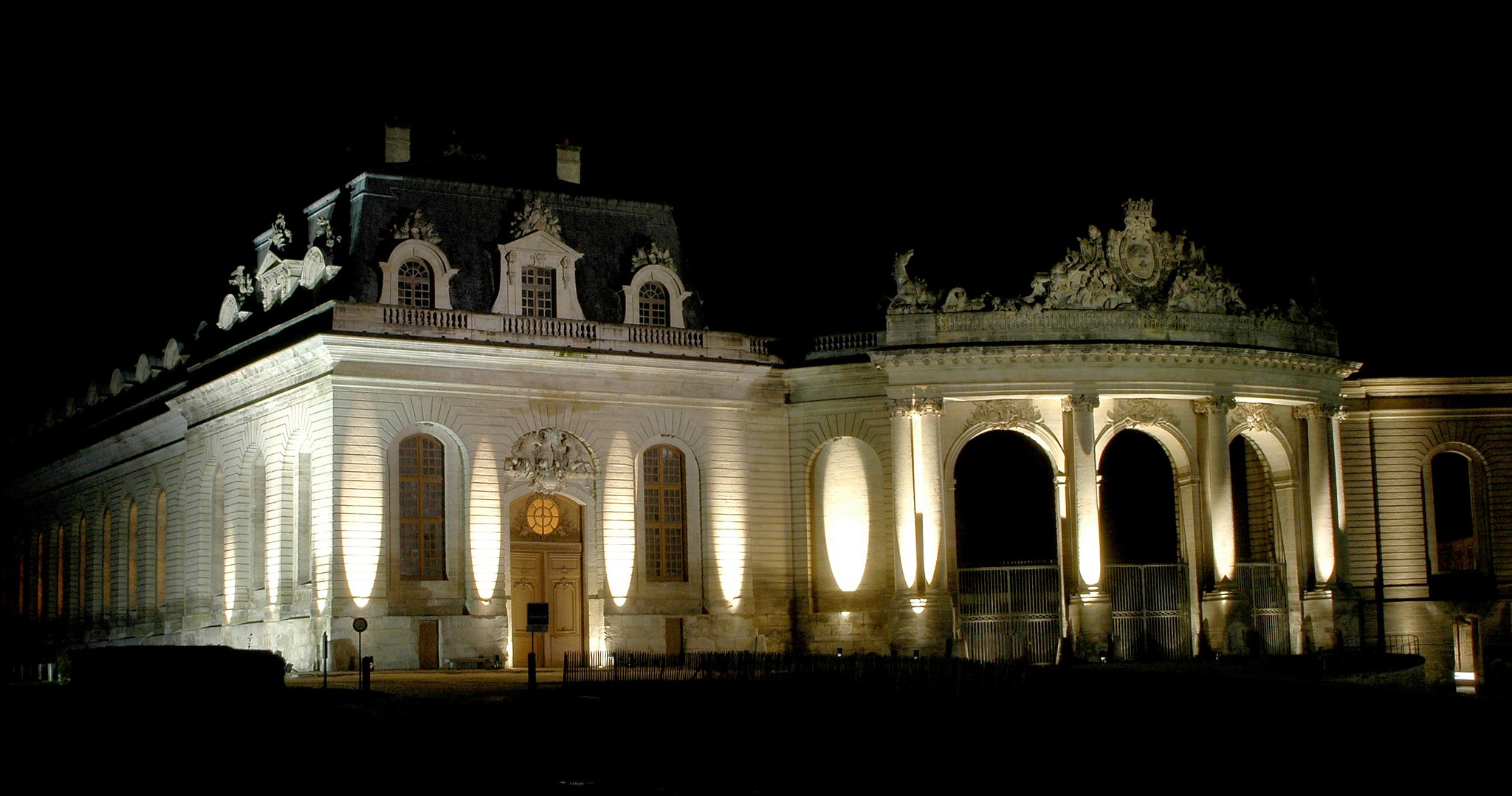 Illuminated historic building with ornate sculptures and arched gates at night.