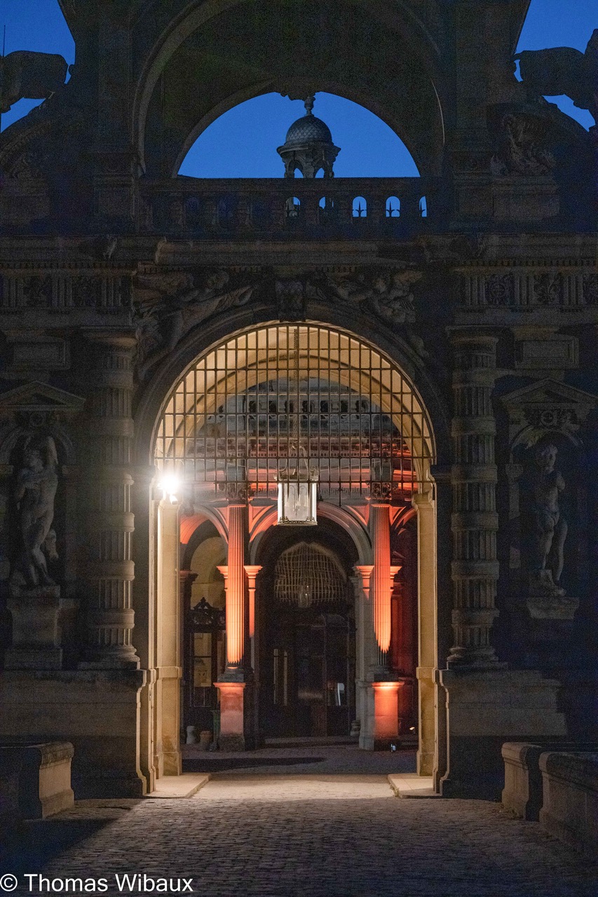 Illuminated ornate stone archway and pillars at night with warm lighting inside a historic building.