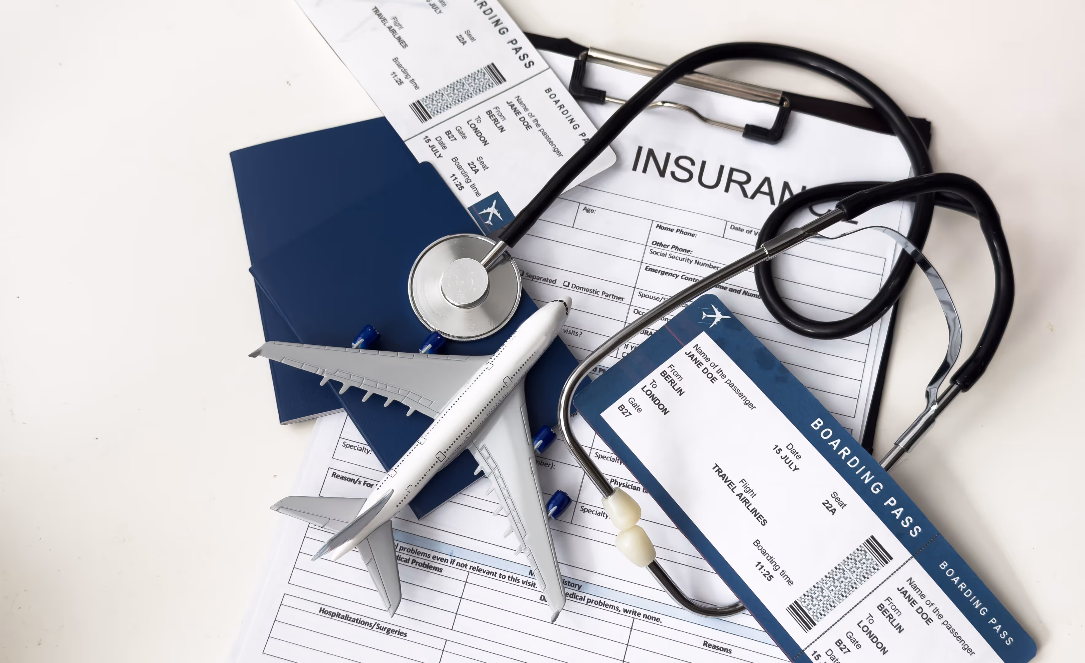 Travel insurance application form, stethoscope, plane model and flight tickets on black wooden table, closeup