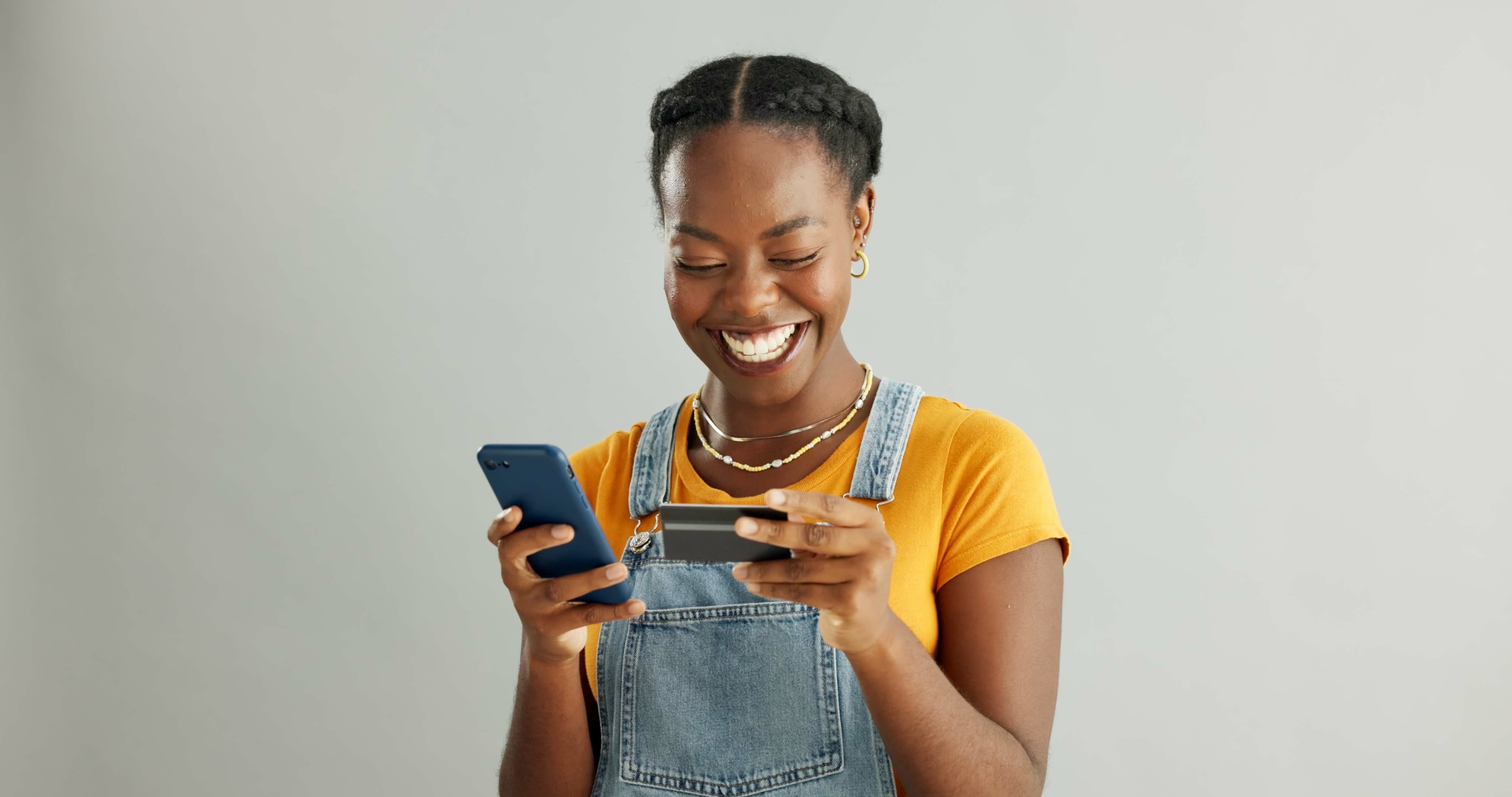 A black woman smiling while holding her phone