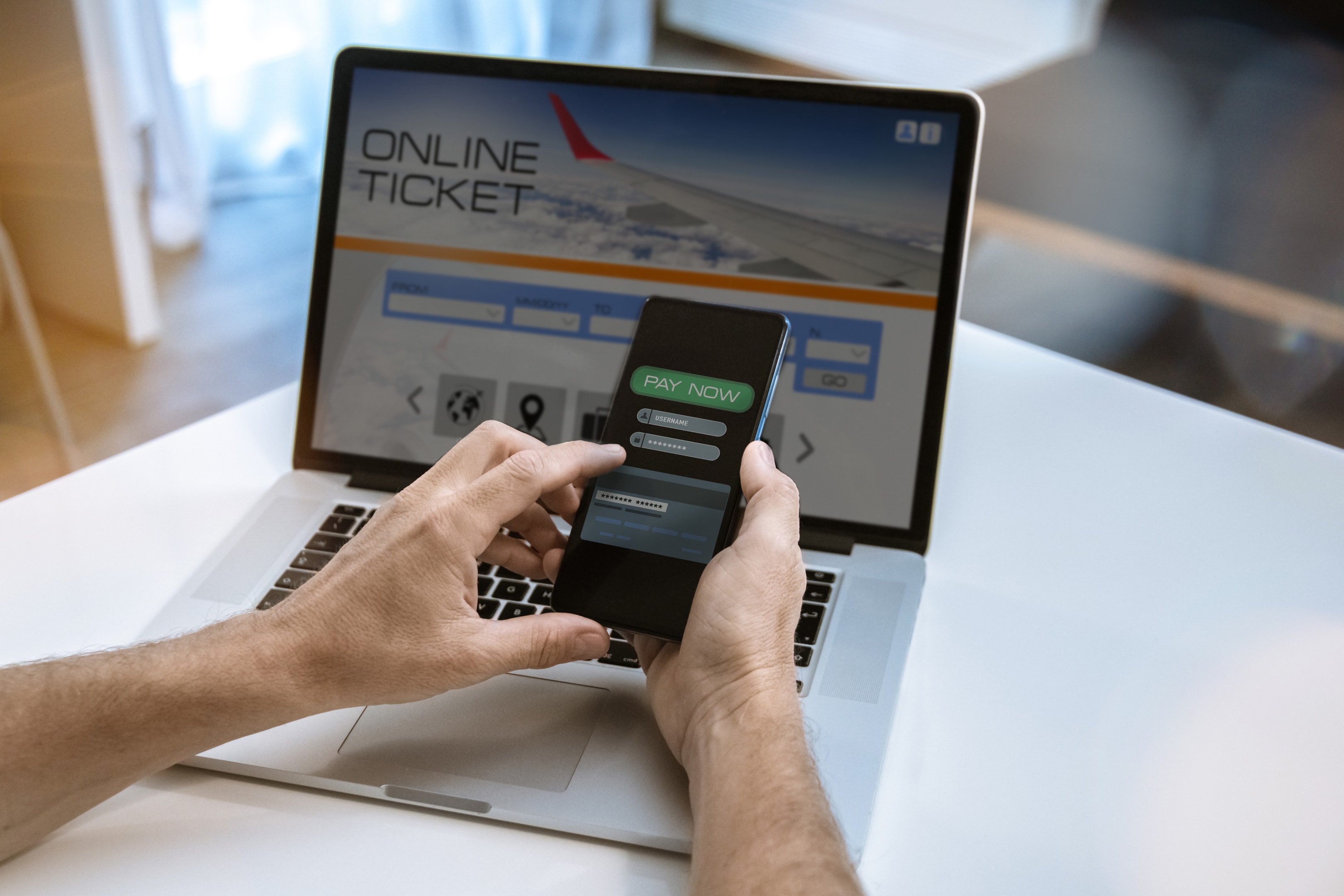 A Hand holding a phone infront of a laptop