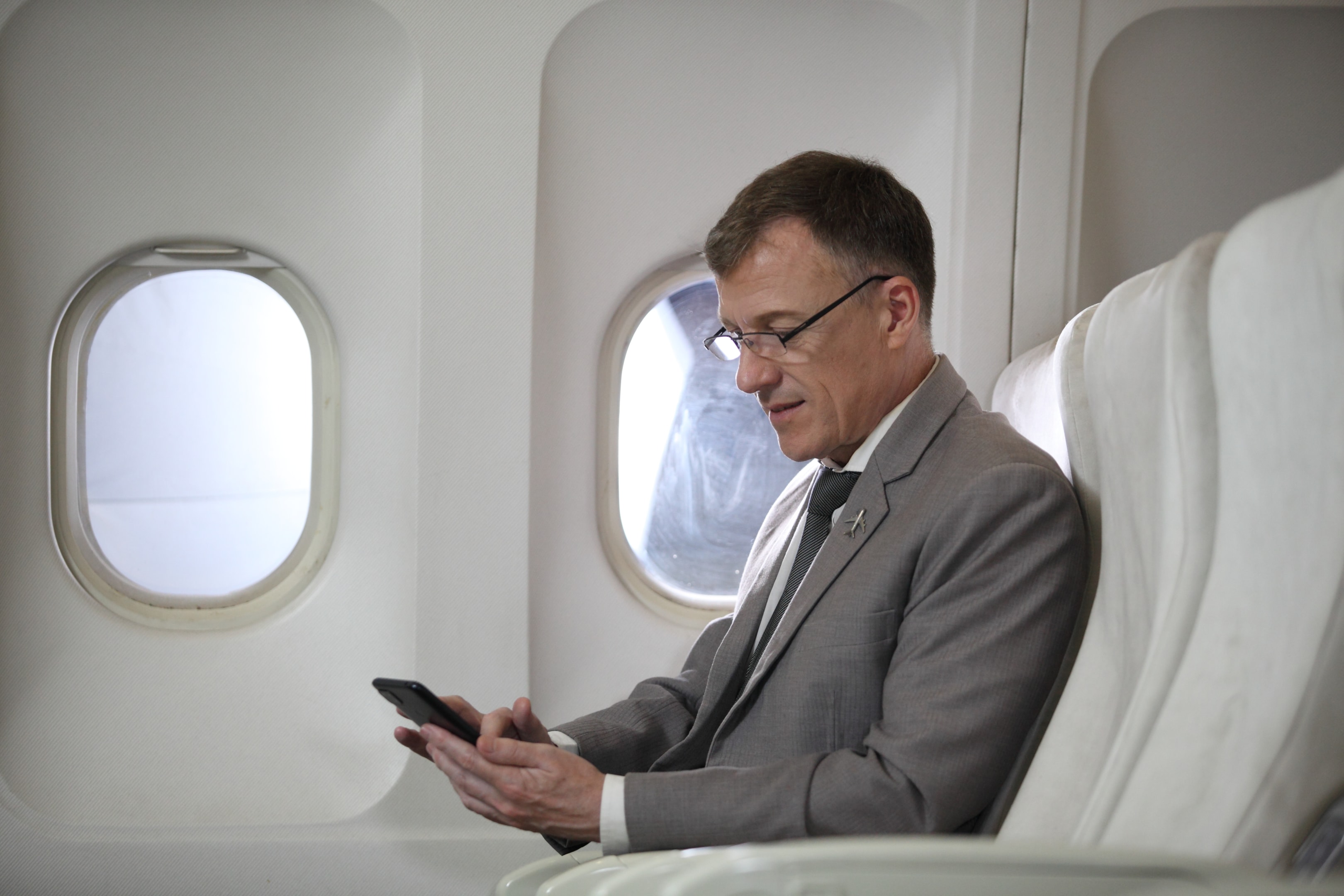 A men passenger using his phone iside the aircraft