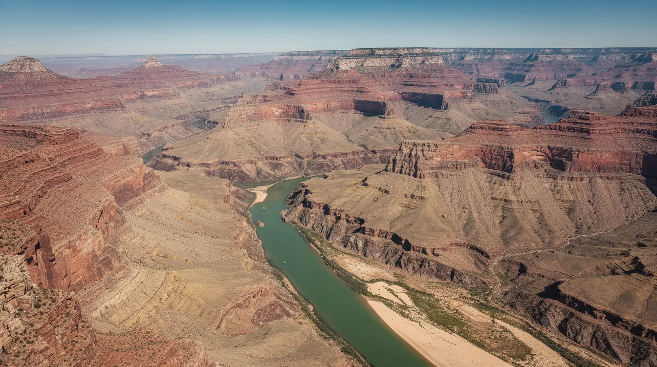 An aerial view of the Grand Canyon showcases its stunning layered red rock walls, with the Colorado River meandering through the canyon floor, creating a breathtaking natural landscape that attracts many travelers on their journey from Las Vegas to Arizona. This beautiful scenery is a must-visit for those exploring the wonders of the West.