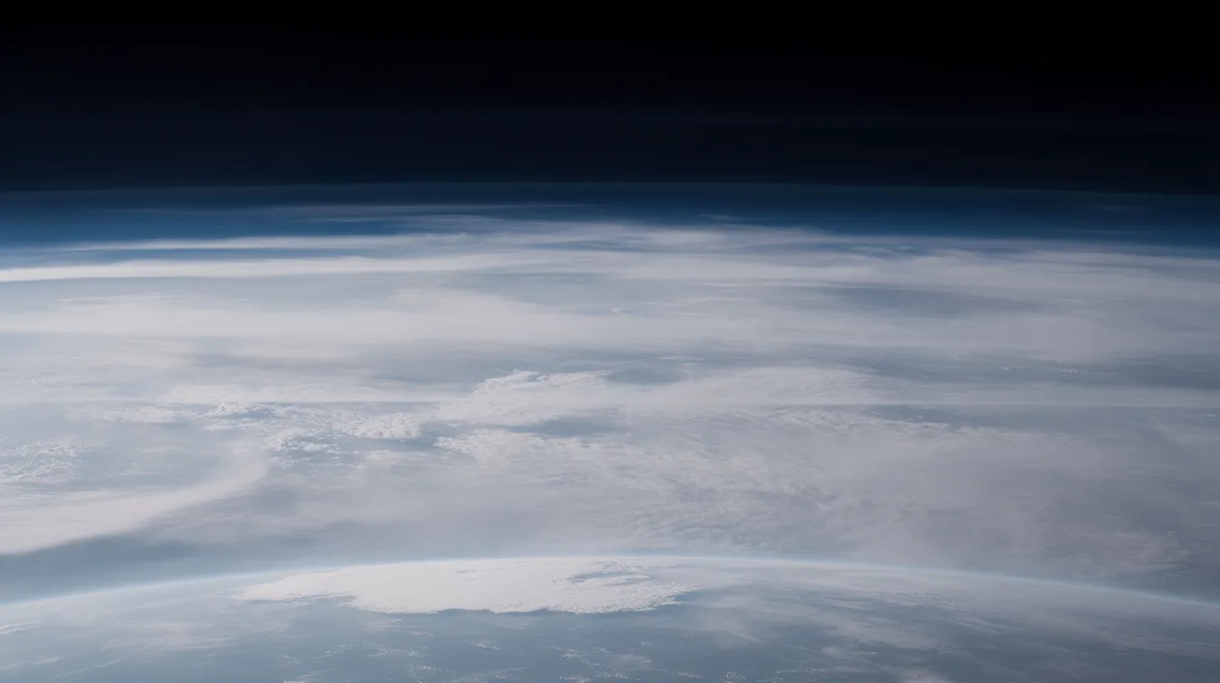 A dramatic high-altitude view reveals distinct atmospheric layers with wispy clouds and a clear sky above, showcasing the complex interactions of air currents and wind shear that can generate clear air turbulence. This image emphasizes the importance of understanding flight levels and wind speed for pilots and airlines to ensure safe travel.