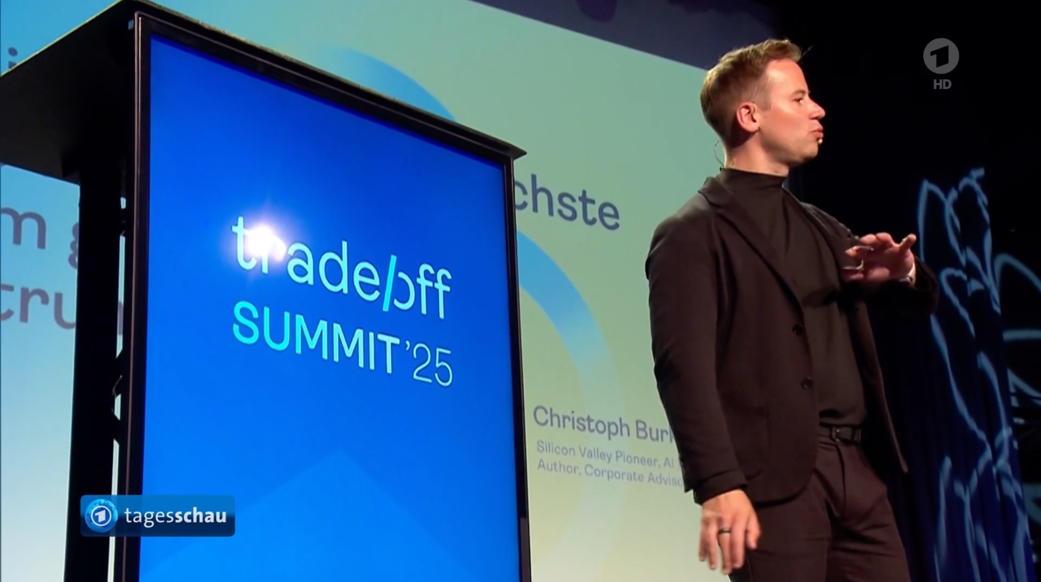 Tagesschau-Bild vom trade/off Summit 2025 mit Logo auf der Bühne