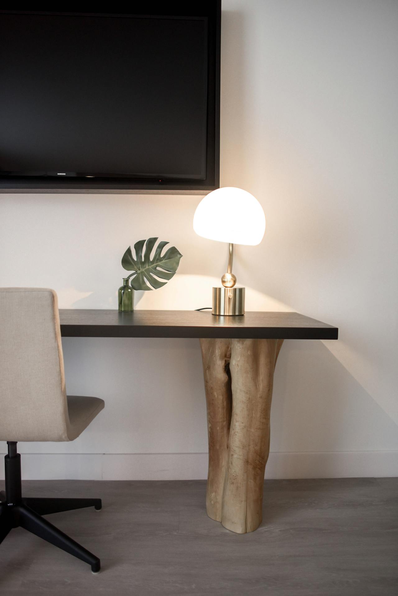 A table with a lamp and a chair next to it.