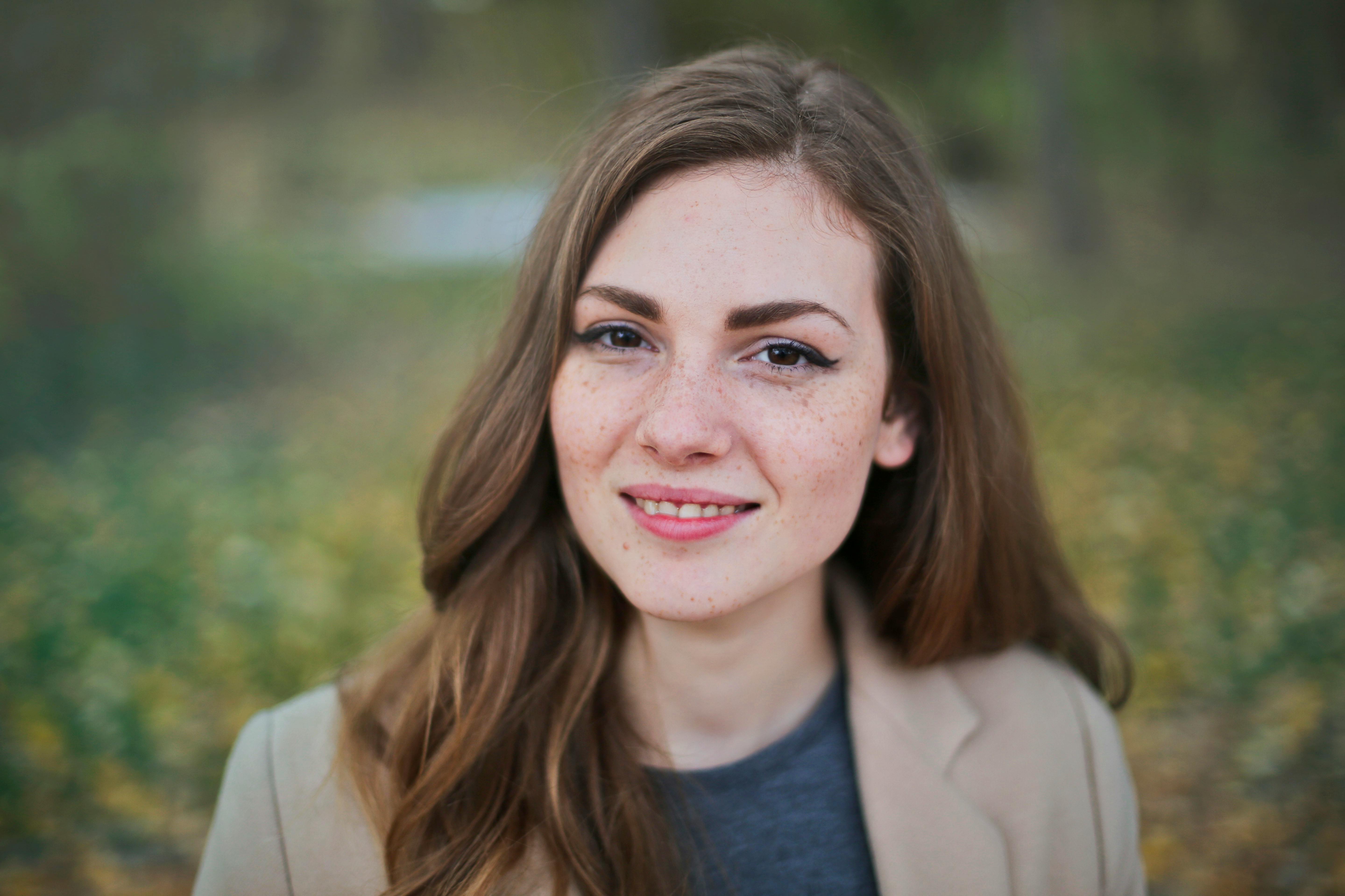 A woman with freckled hair and blue eyes smiles at the camera.