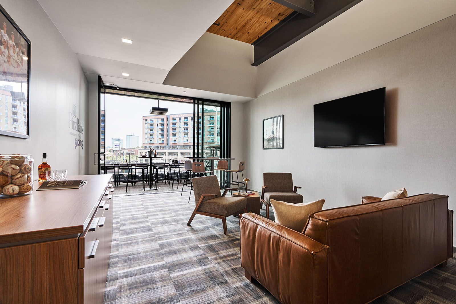 leather couch with wooden cabinet and tv mounted with overhead lighting