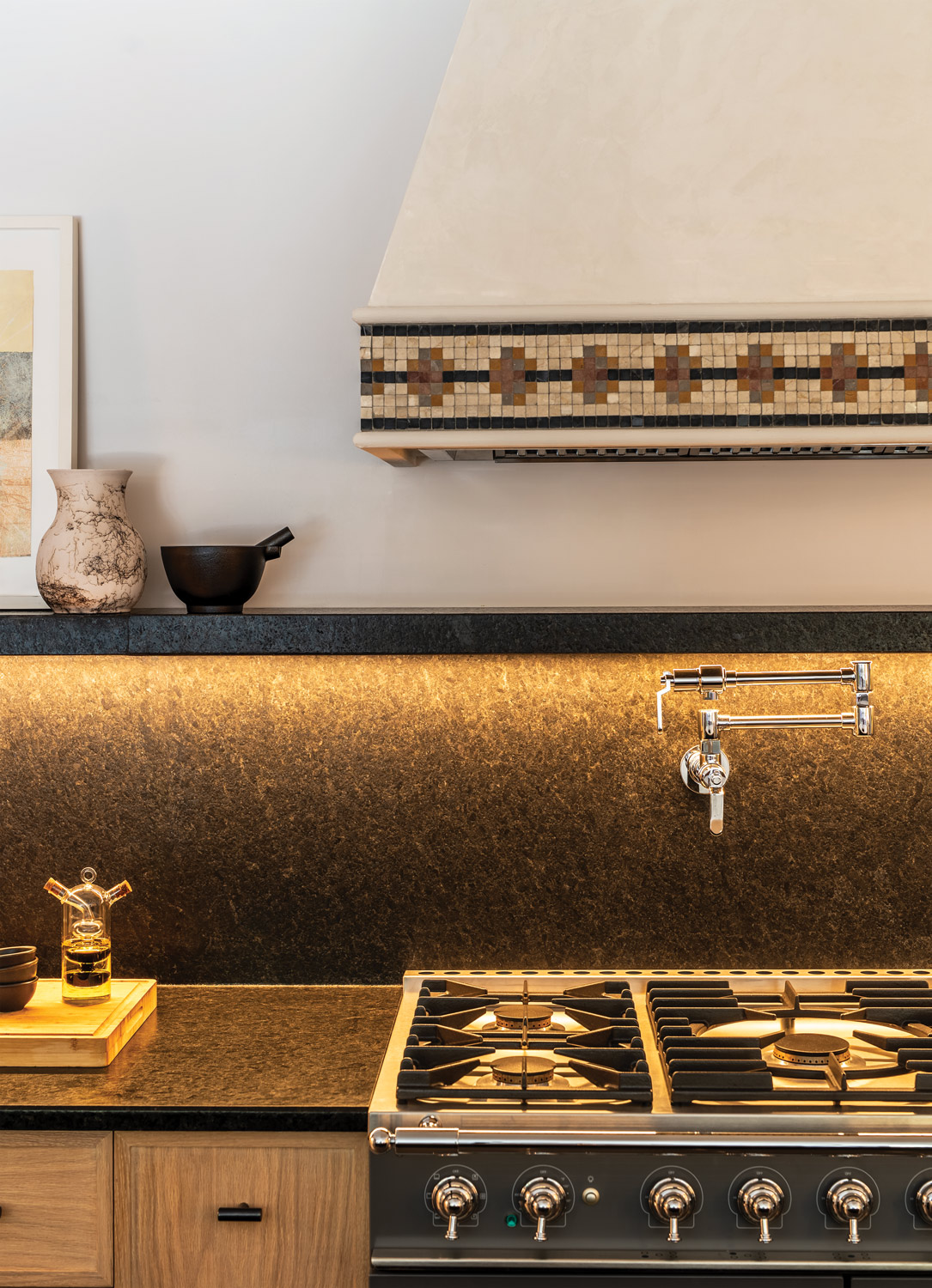 tiled oven hood above pot filler faucet and under glow lighting