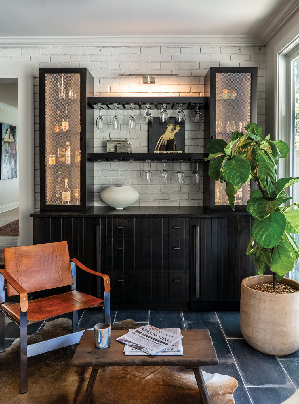 black wooden wine nook behind a leather chair fitted with custom artwork