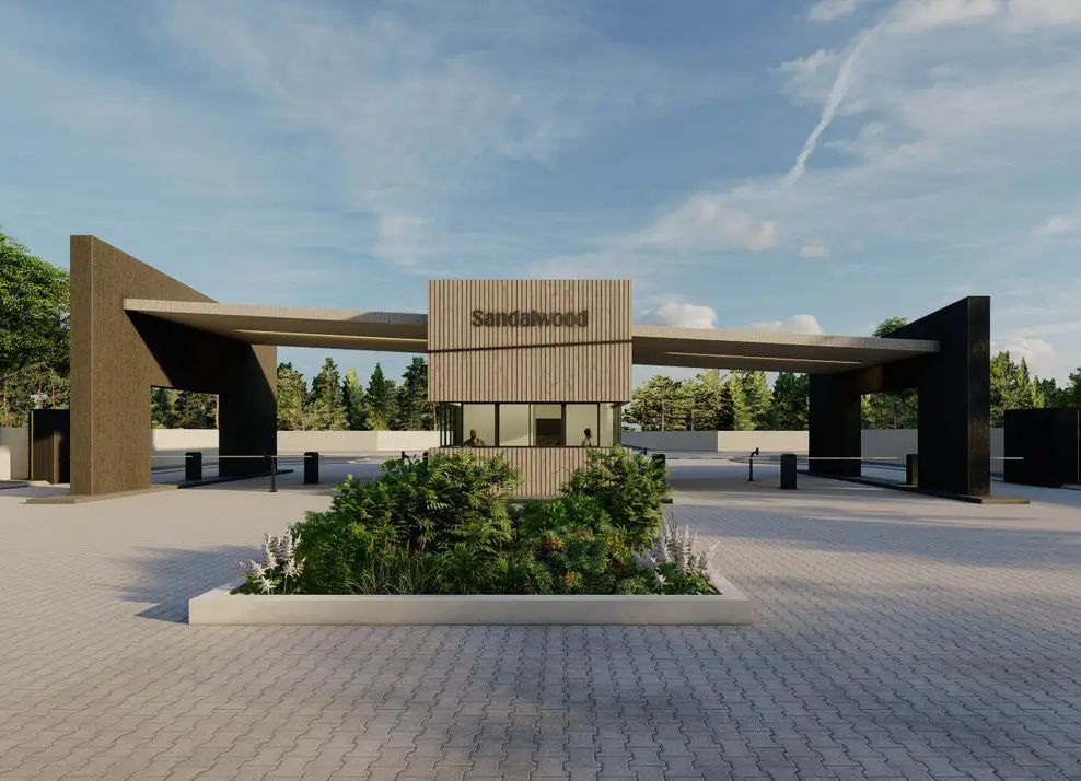 Modern gated entrance with a central booth labeled Sandalwood, flanked by large wooden canopy structures and surrounded by greenery.