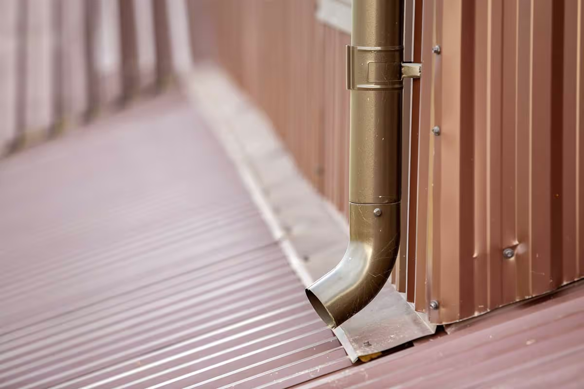 Gutter and downspout running down the side of a metal building