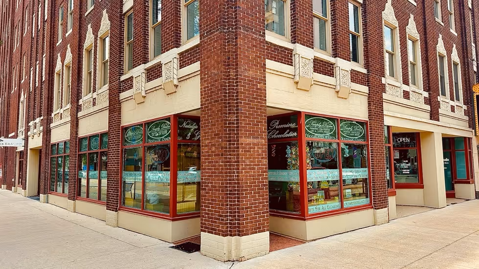 Corner view of the Simply Divine Candy shop storefront in a restored brick building near the Paramount Theatre in Cedar Rapids, Iowa