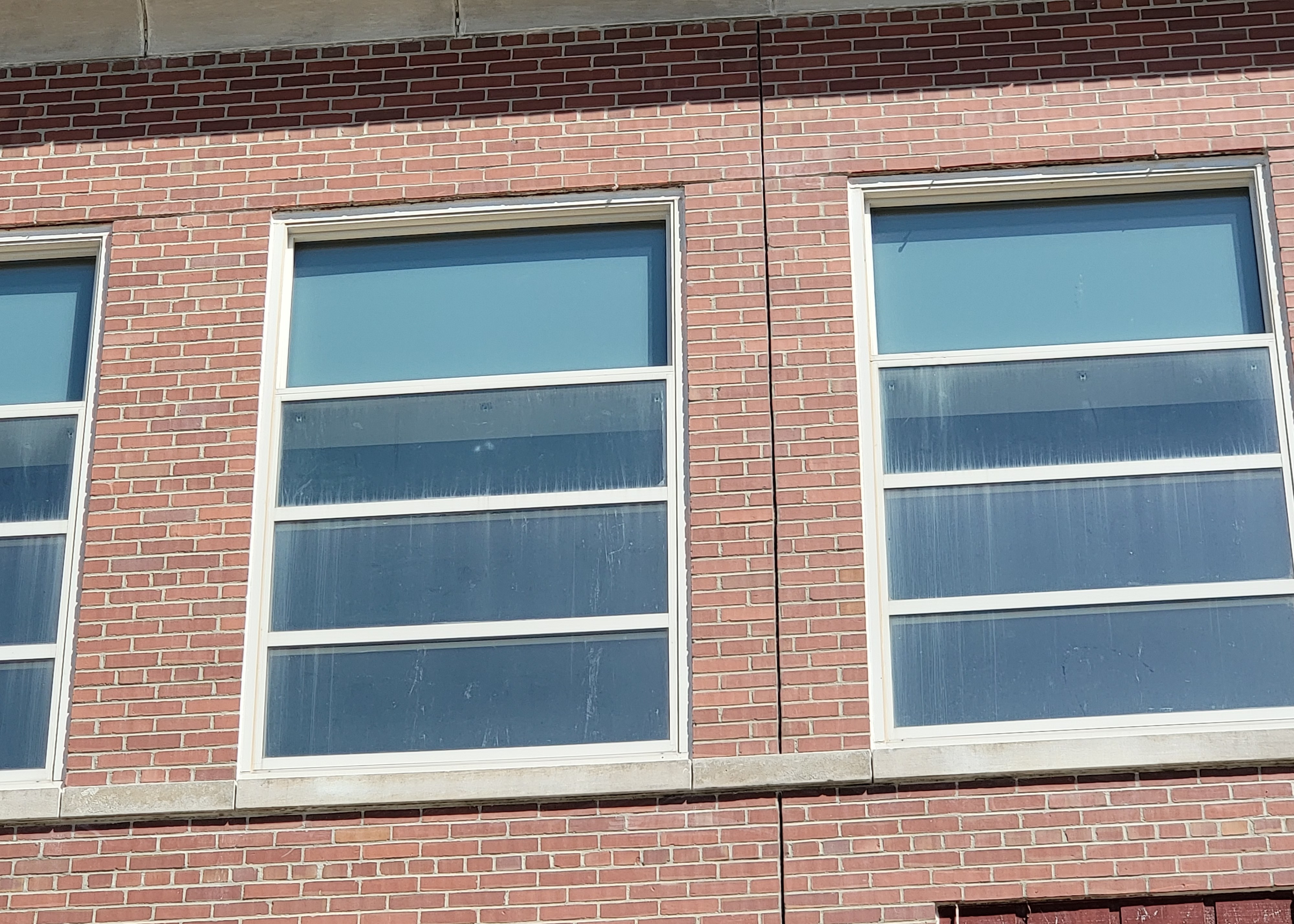 Cracked mortar and separating sealant above a window frame, caused by a deflecting lintel.