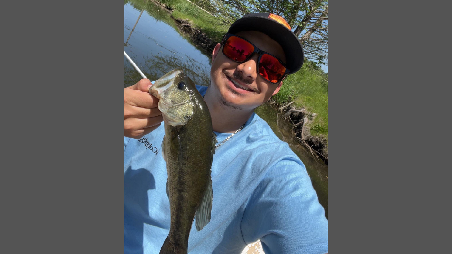 Victor Guzman, tuckpointer at TNT Tuckpointing, smiling and holding a fish he caught while enjoying his favorite hobby outside of work.