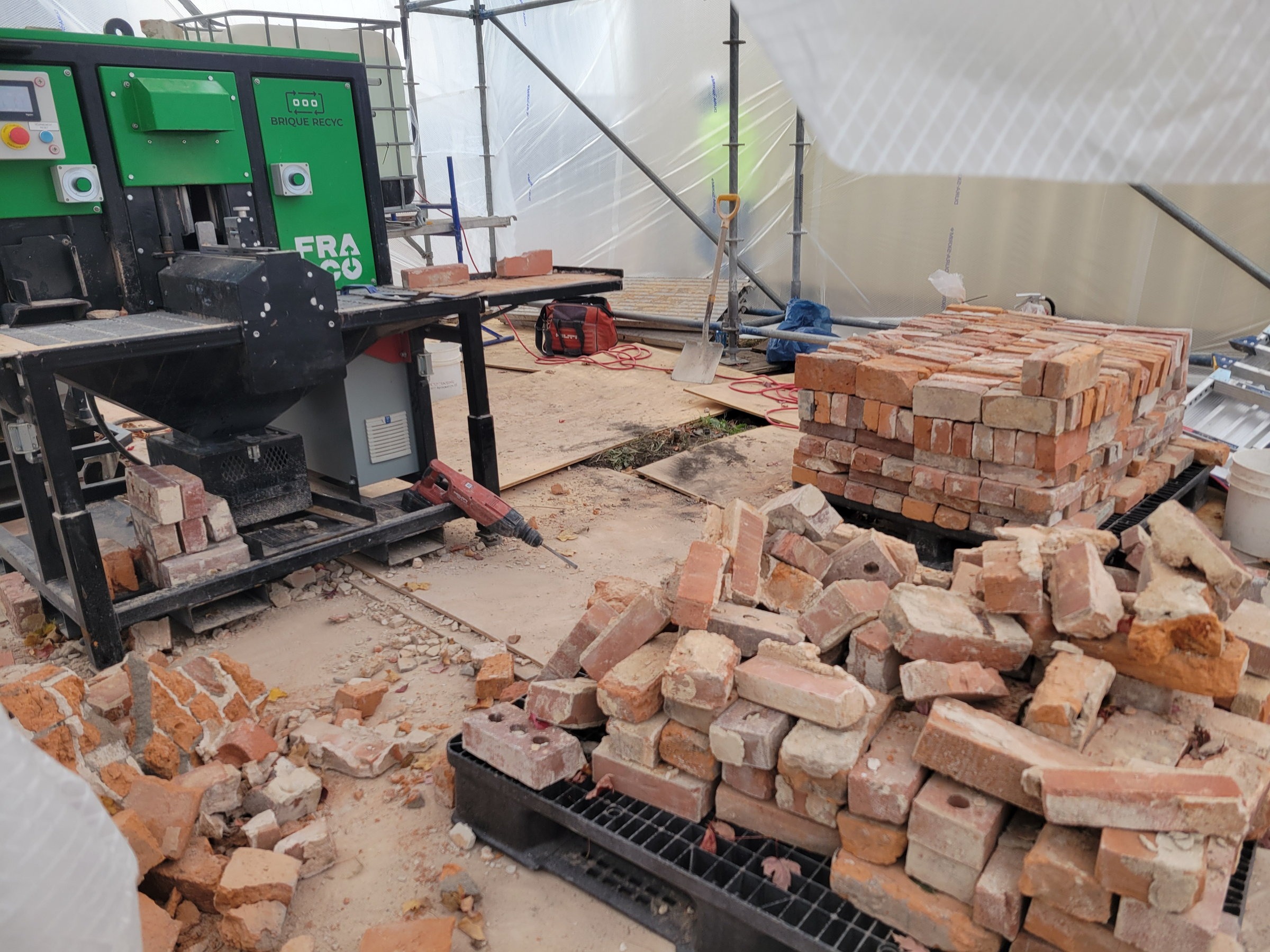 Salvaged historic brick being cleaned and sorted for reuse inside the enclosure