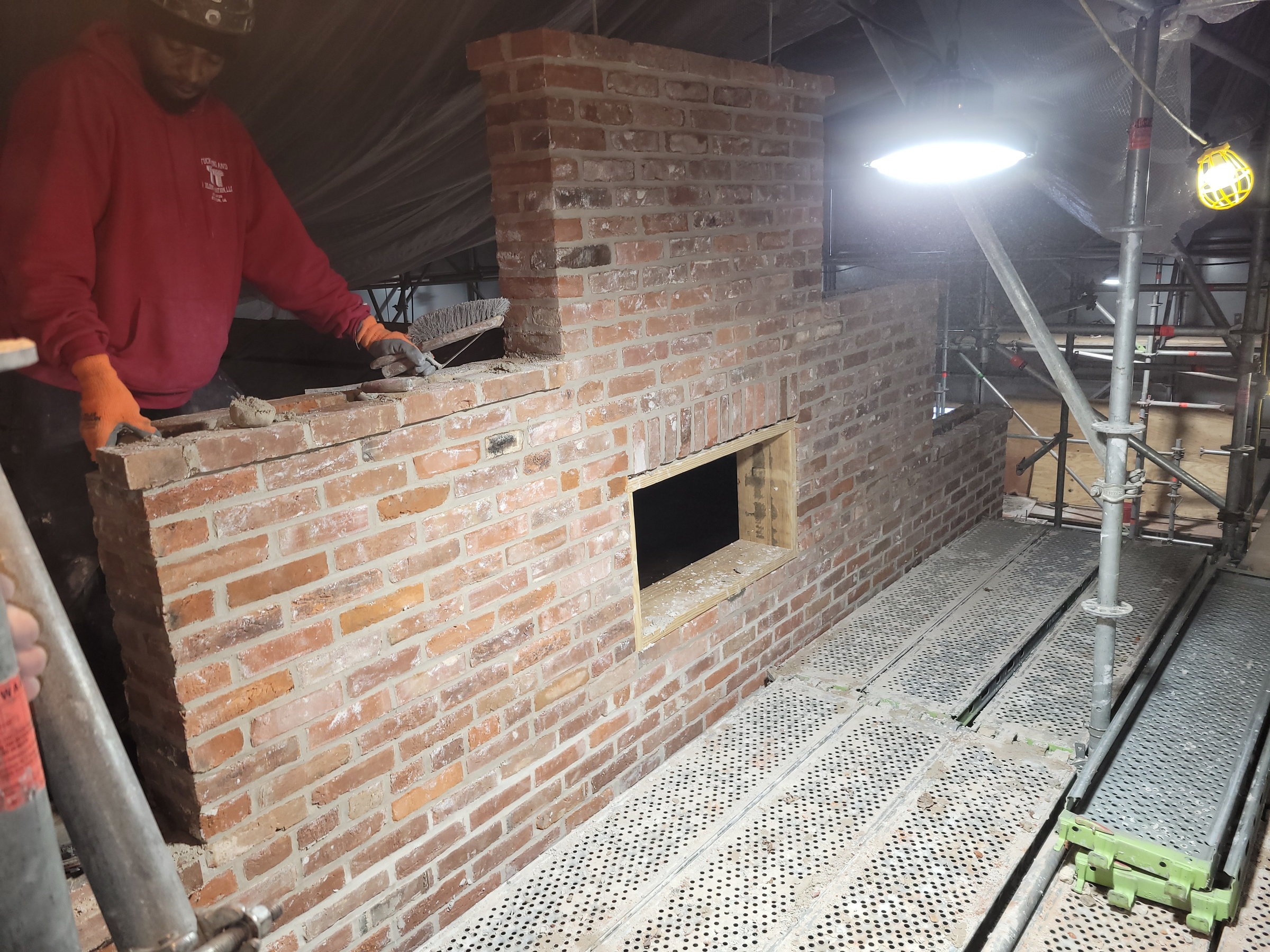 TNT mason brushing out fresh joints on a rebuilt wing wall laid to match the irregular original coursing