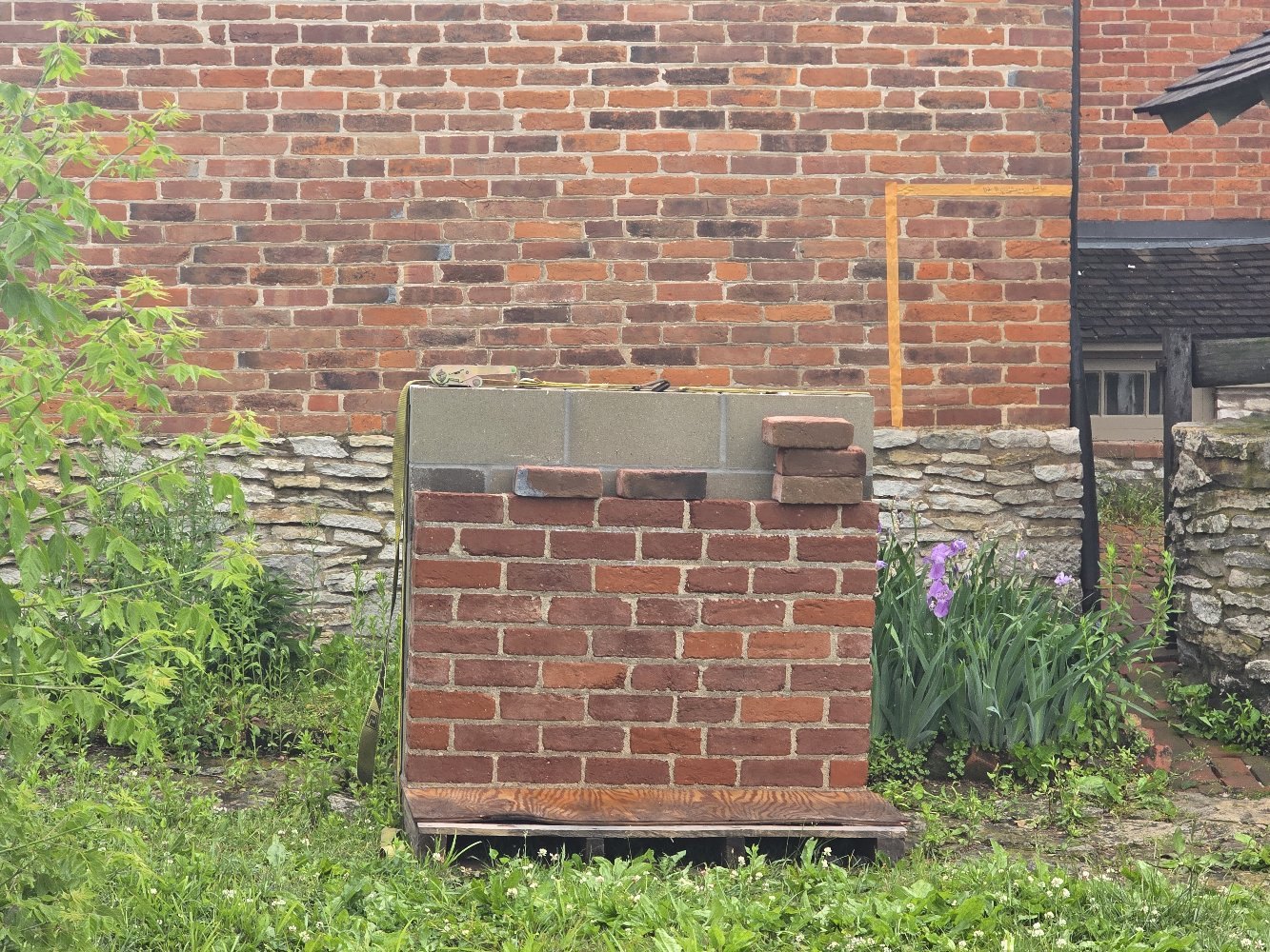 Brick mockup panel with staining samples set up beside the original house wall to judge the color match