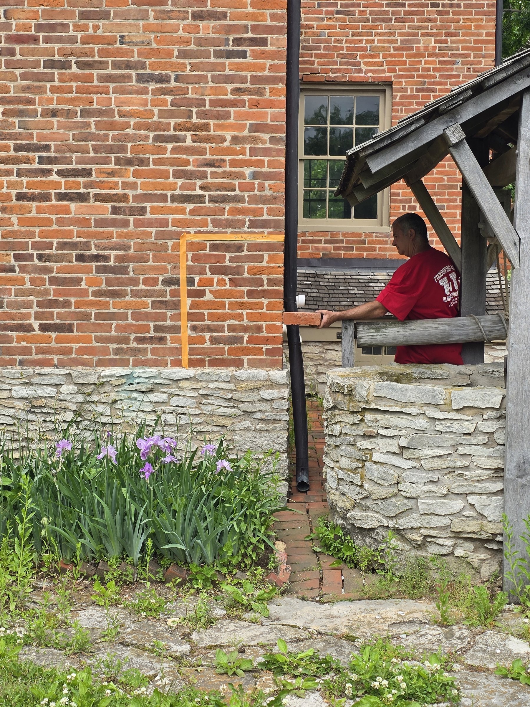 Taped cleaning test panel on historic brick beside the stone well at the Brigham Young Home